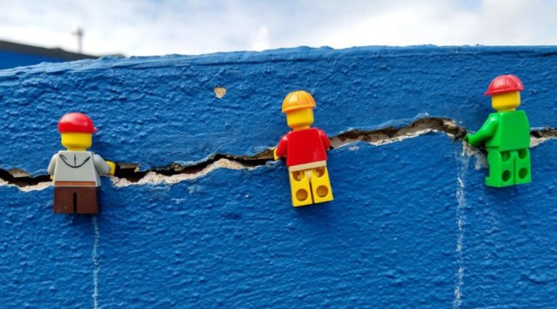 School sets LEGO minifigures to work repairing a cracked wall